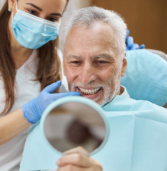 A man at the dentist looking at his smile in a mirror