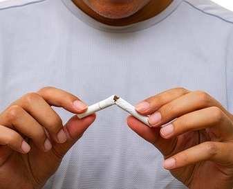 A man breaking a cigarette in half