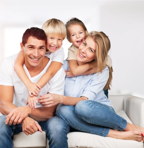 Smiling family of four sitting on white couch