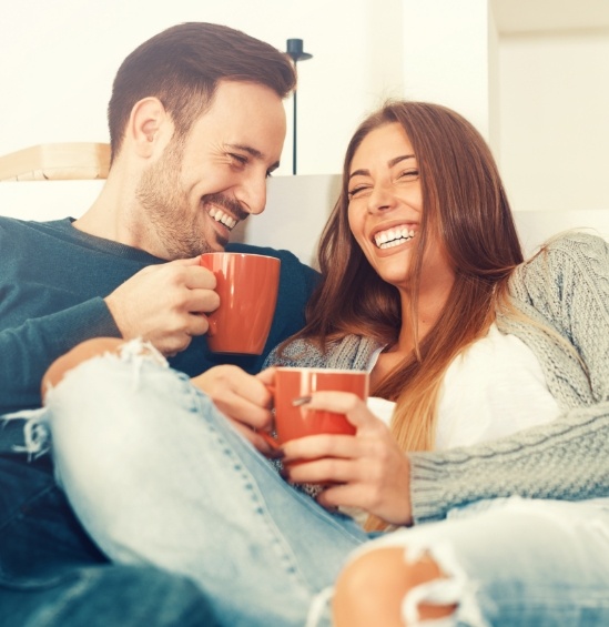 Laughing man and woman each holding red coffee mug