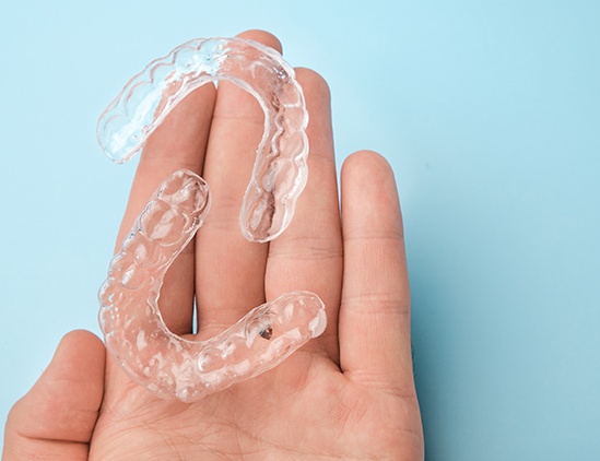 Bird’s-eye-view of two clear aligners resting on the palm of a hand