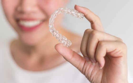 Smiling person holding clear aligner in Fresno