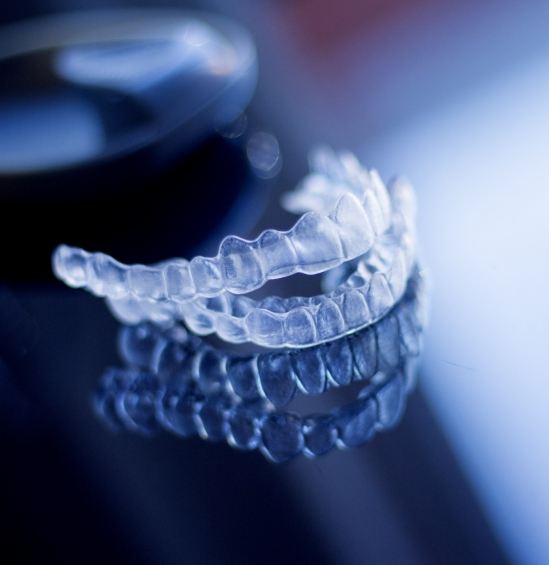 Two clear aligners on dark surface
