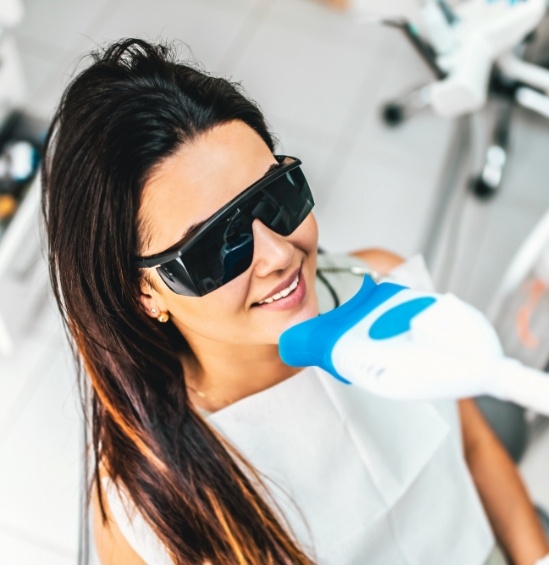 Woman having her teeth professionally whitened in dental office