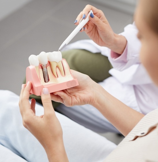 Dentist showing a dental implant model to a patient