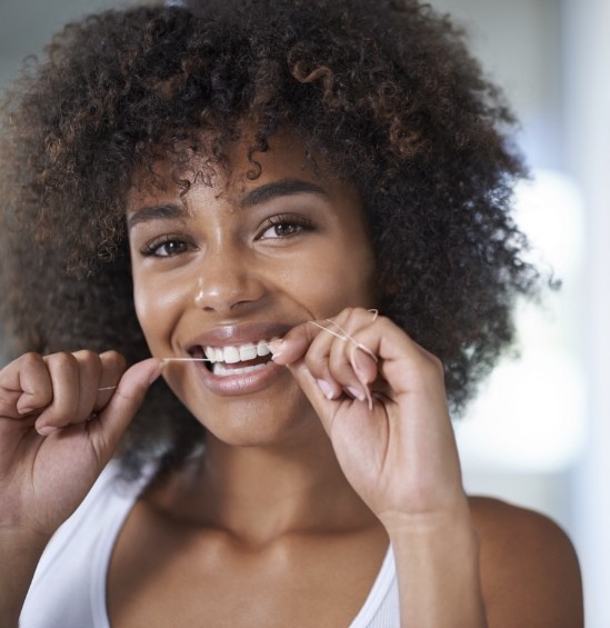 Woman smiling while flossing her teeth