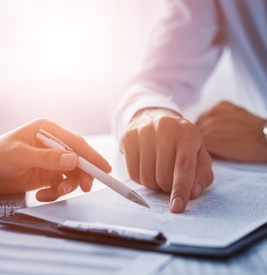 Person showing another person where to sign on dental insurance form