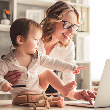 Mother looking at laptop and holding baby pointing to laptop