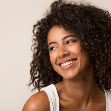 Woman in white tanktop smiling and looking to the side