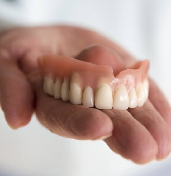 Dentist holding full upper denture in their hand