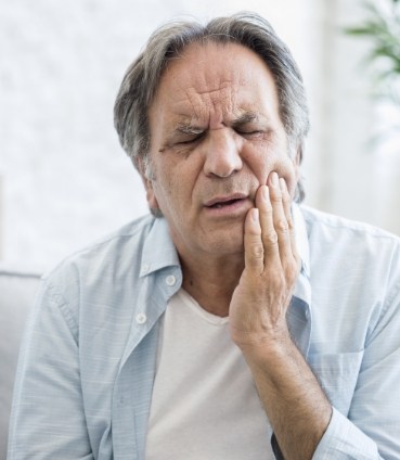 Senior man holding the side of his face in pain