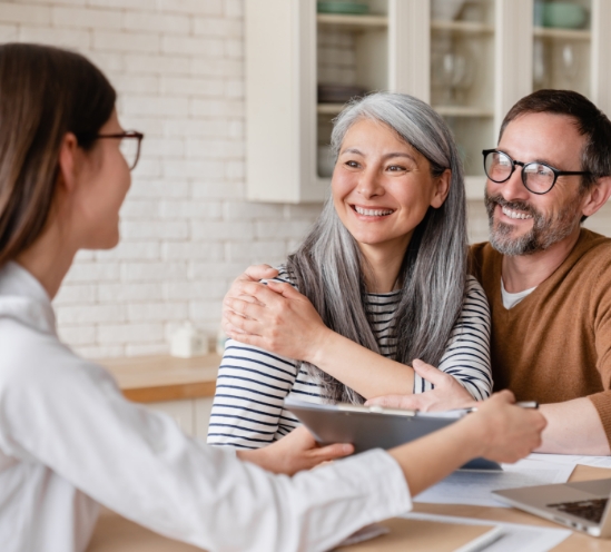 Man and woman holding hands while talking to woman sitting across table from them