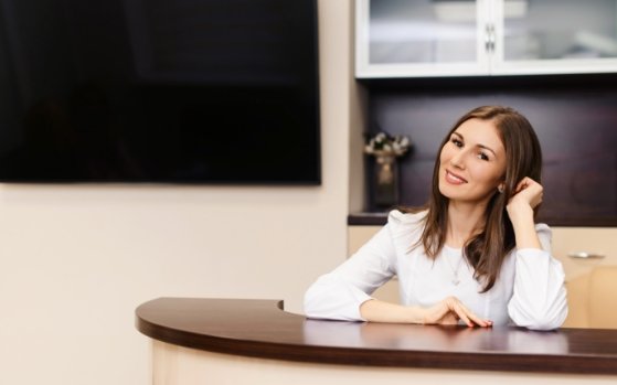 Smiling dental team member sitting at desk