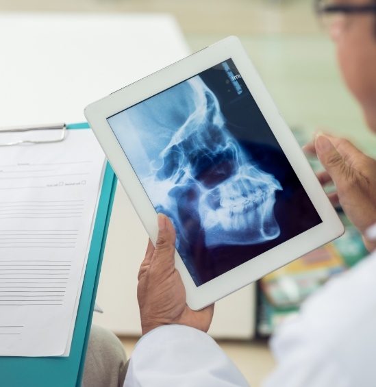 Dentist looking at x ray of jaw on tablet