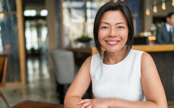 Smiling woman in coffee shop after tooth extractions in Fresno