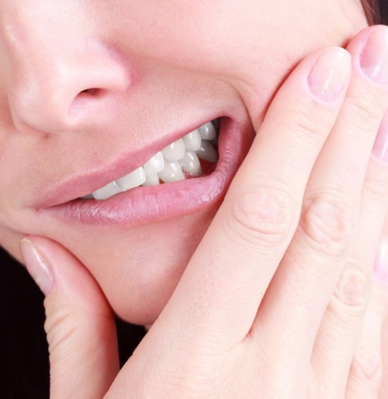 Close up of person holding their cheek in pain