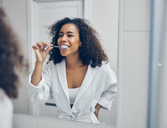 Woman brushing teeth after teeth whitening in Fresno