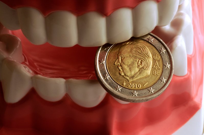 Model of teeth with good dental health biting a coin