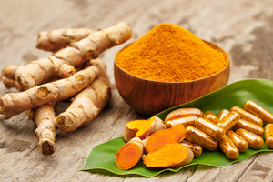 Bowl of turmeric powder next to turmeric capsules